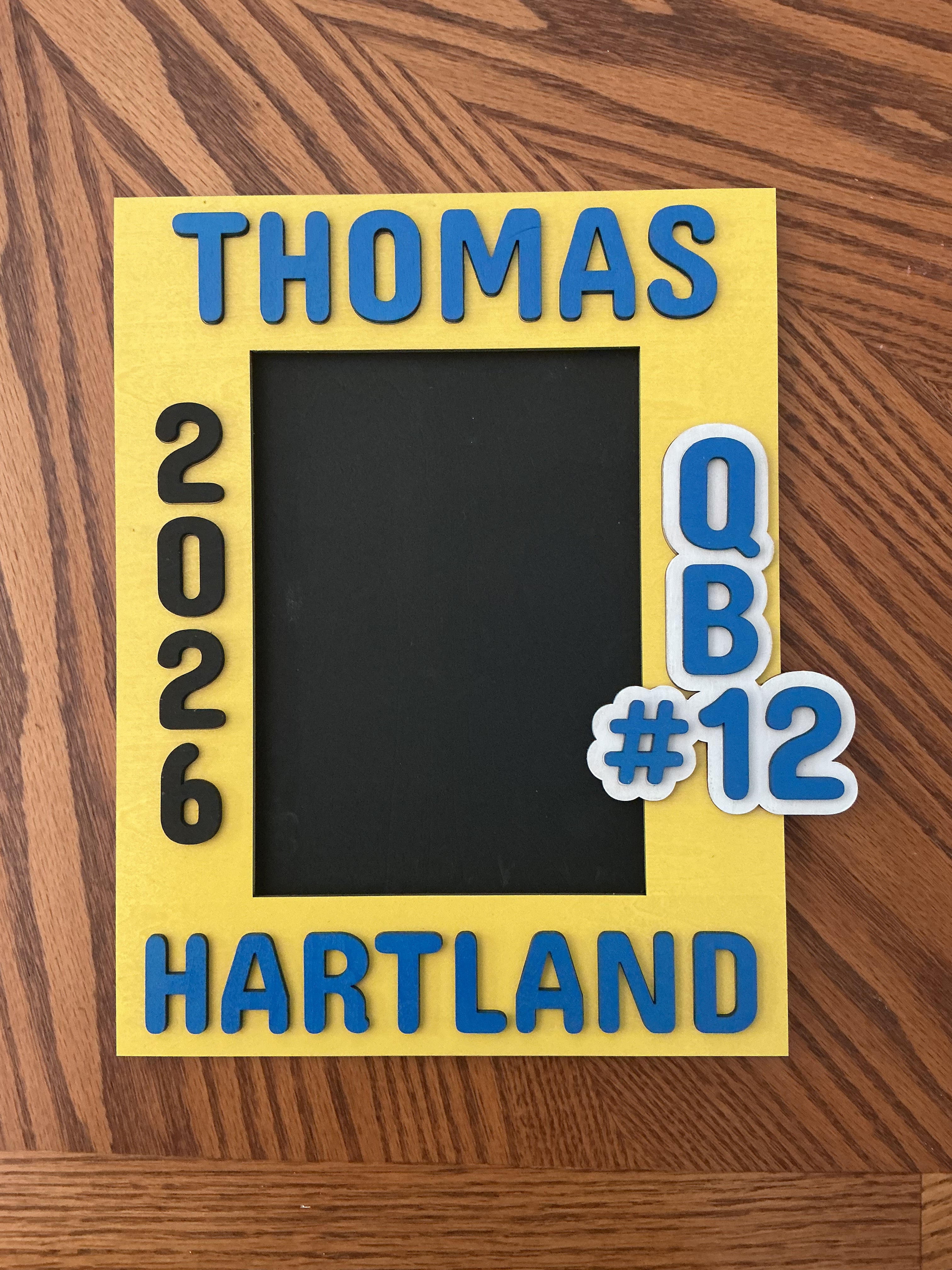 "Yellow and blue painted wood laser engraved football picture frame with name, city, jersey number, and year"