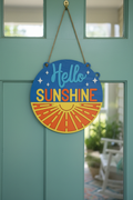 Round blue and orange laser engraved wood sign reading Hello Sunshine with rising sun hanging on a summer front door