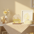 Personalized wood school bus birth announcement sign on a nursery shelf with pastel yellow decor
