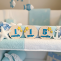 Circular dolphin monthly milestone markers with blue numbers and yellow stars in pastel ocean nursery