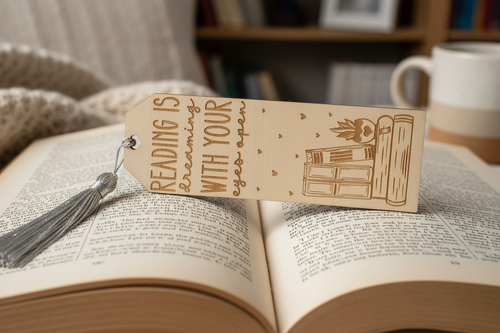 Reading is Dreaming With Your Eyes Open laser engraved wood bookmark with silver tassel resting on open book lifestyle photo