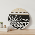 Welcome Modern Cube circular laser engraved wood sign leaning against white wall with neutral home decor