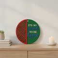 It's So Good To Be Home Geo Bold circular laser engraved wood sign leaning against white wall with neutral home decor