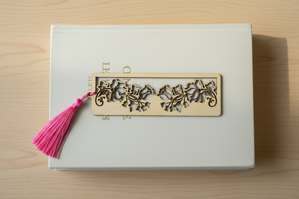 Floral filigree laser cut wood bookmark with pink tassel flat lay on closed book cover