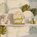 Personalized wood dinosaur birth announcement sign on a nursery shelf with pastel green decor