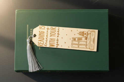 Reading is Dreaming With Your Eyes Open laser engraved wood bookmark with silver tassel flat lay on closed book cover