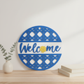 Welcome Sunflower Lattice circular laser engraved wood sign leaning against white wall with neutral home decor